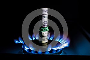 A hundred dollar bill on a gas burner with a burning fire on a black background, the front and back background is blurred with a