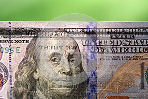 Hundred dollar bill on light against blurred green background