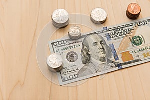 A hundred dollar bill surrounded by a stack of coins