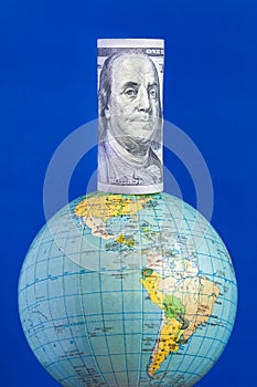 A hundred-dollar bill on top of the globe