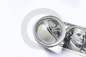 Hundred dollar bill under a magnifying glass ball is being inspected Conceptual photo isolated on white background