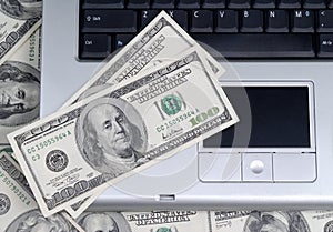 Hundred dollar bills lying on laptop keyboard