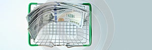 Hundred dollar bills in shopping basket closeup