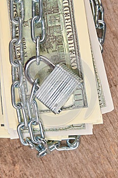 Hundred dollars banknotes secured with a chain and lock.