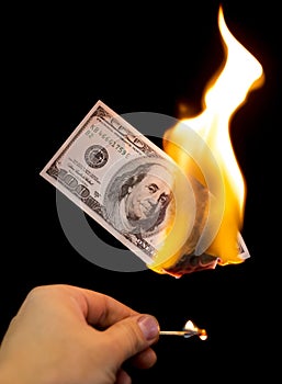 A hundred dollars burn in a fire on a black background