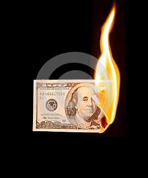 A hundred dollars burn in a fire on a black background