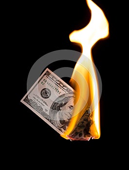 A hundred dollars burn in a fire on a black background