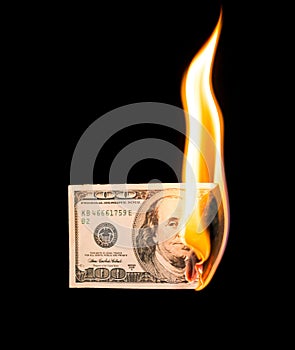 A hundred dollars burn in a fire on a black background