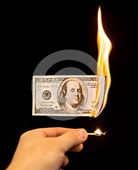 A hundred dollars burn in a fire on a black background