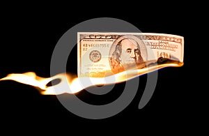 A hundred dollars burn in a fire on a black background