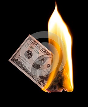 A hundred dollars burn in a fire on a black background