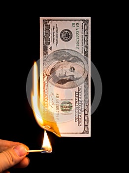 A hundred dollars burn in a fire on a black background