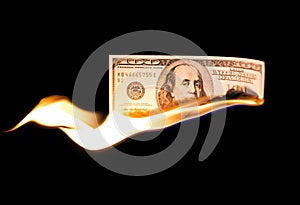 A hundred dollars burn in a fire on a black background