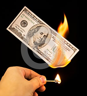 A hundred dollars burn in a fire on a black background