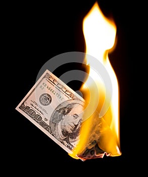 A hundred dollars burn in a fire on a black background