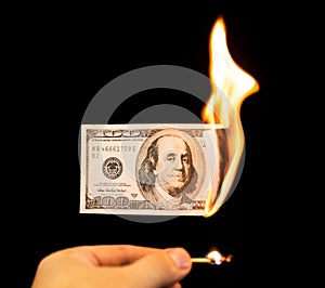 A hundred dollars burn in a fire on a black background