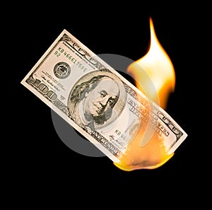 A hundred dollars burn in a fire on a black background