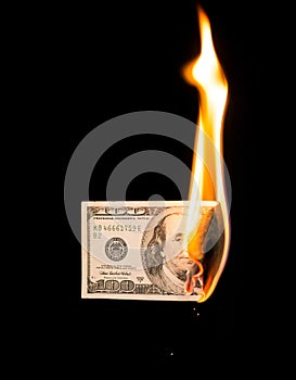A hundred dollars burn in a fire on a black background