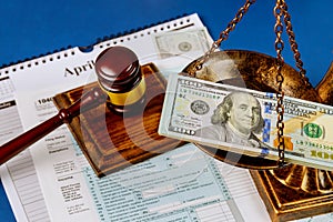 Hundred US dollar bills on a table scales of justice, gavel IRS form. 1040 U.S tax forms April 15 of the deadline time tax season