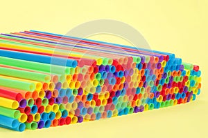 Hundreds of colorful plastic straws on a yellow background