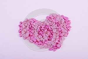 Hundreds of tiny pink heart-shaped hearts lie in the shape of a large heart as a symbol of romantic love