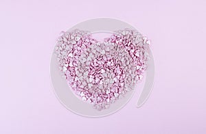 Hundreds of tiny pink heart-shaped hearts lie in the shape of a large heart as a symbol of romantic love