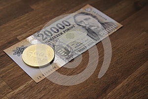 Hungarian forint 20 000 forint banknote Ferenc DeÃ¡k. Brown wooden table. Next to it is a gold bitcoin digital cryptocurrency coin