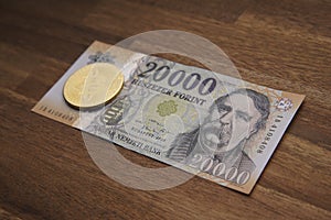 Hungarian forint 20 000 forint banknote Ferenc DeÃ¡k. Brown wooden table. Next to it is a gold bitcoin digital cryptocurrency coin