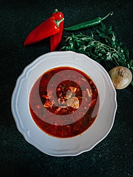 Hungarian Goulash soup with pepper in a white plate on a dark background