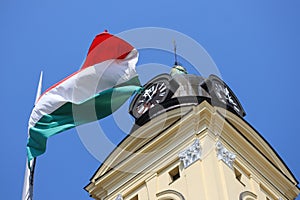 Hungarian national flag next to the tower of the great church