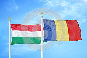 Hungary and Romania two flags on flagpoles and blue cloudy sky