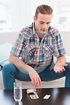 Hungover man with his medicine laid on coffee table photo