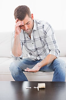 Hungover man with his medicine laid out on coffee table