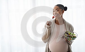 Hungry african american pregnant woman enjoying fresh vegetable salad