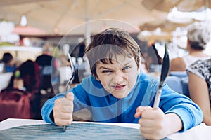 Hungry angry little boy waiting for his dinner