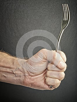 Hungry and angry male hand holding fork