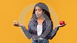 Hungry Black Woman Holding Burger And Apple Fruit