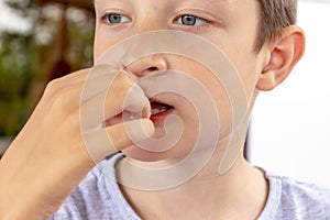 A hungry boy eating a fried potatoes on the summer terrace of the city fast food restaurant, close up view