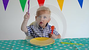 Hungry boy with fork and spoon sitting in front empty plate. Gimbal motion