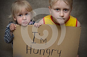 A hungry boy and a girl with a cardboard tablet with the inscription I`m hungry . The social problem. photo