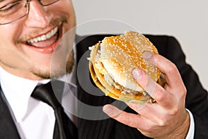 Hungry businessman eating hamburger