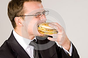 Hungry businessman eating hamburger