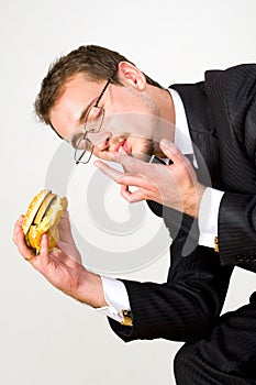 Hungry businessman eating hamburger