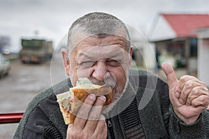 Hungry Caucasian senior driver eating lyulya kebab in lavash near his car