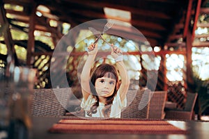 Hungry Child Holding Fork and Knife in a Restaurant