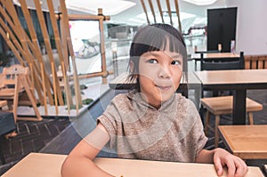 Hungry child licking her lip waiting for food in restaurant