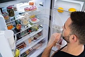 Hungry Confused Man Looking In Open Fridge