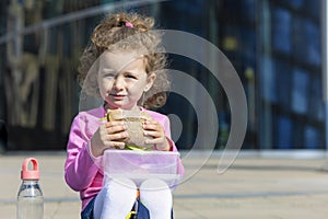 Hungry cute child with appetite eating fast food, portrait. happy girl biting homemade sandwich. harmful, unhealthy, healthy meal.