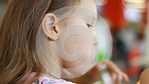 Hungry funny baby girl eating burger in fastfood cafe. Child eats food closeup