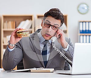 Hungry funny businessman eating junk food sandwich